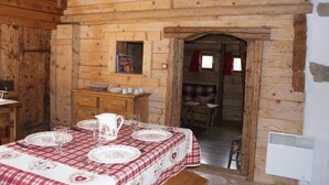Een houten hut interieur met een eettafel voor vier personen, een keukenhoek en een klein raam.