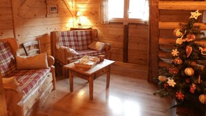 Een gezellig houten interieur met een geruit bankstel, een houten tafel en een versierde kerstboom.