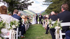 A wedding ceremony outdoors with guests seated on white chairs arranged in rows. - Walk to Vail Village Restaurants,  Shops & Lifts - Epic Views, Top Rated Condo! (Vail)