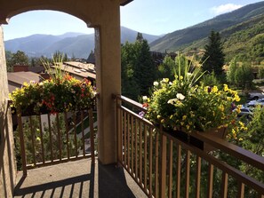 A balcony with a view of mountains and a parking area.