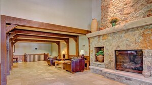 A spacious lobby with a stone fireplace, wooden beams, and a seating area with leather chairs. - Free SkyCard Act-Fitness Center, Gas Fireplace - Highland Greens Lodge 305 (Breckenridge)