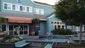 Una tienda Seascape Foods con fachada azul, una fuente y mesas al aire libre.
