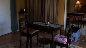 Un comedor con mesa, sillas y alfombra. Se observa una puerta y un espejo al fondo.