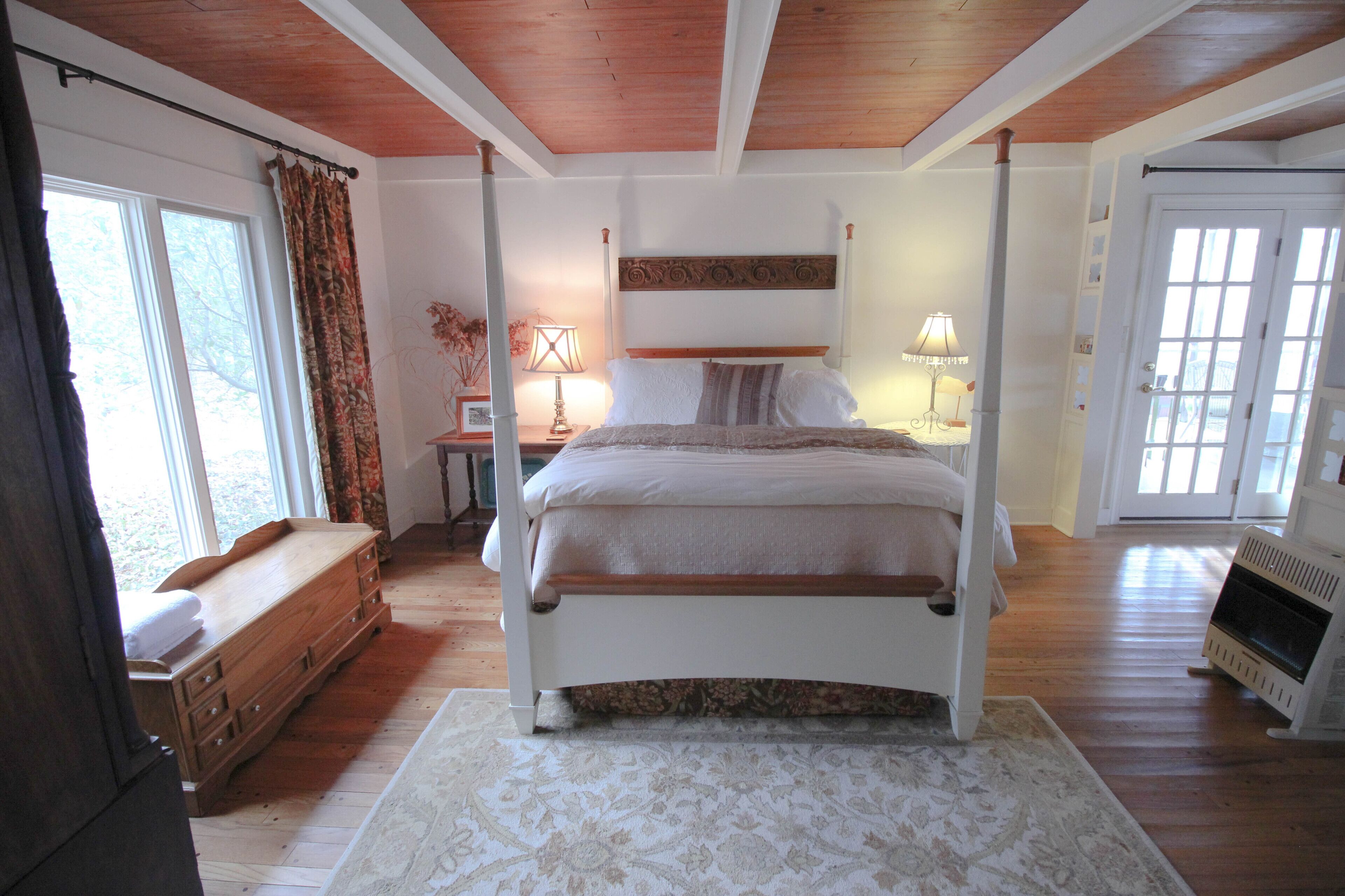 A bedroom with a four-poster bed, wooden dresser, and a radiator.