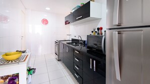 Une cuisine moderne avec des meubles noirs, des appareils en acier inoxydable et un saladier jaune posé sur le plan de travail.