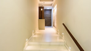 Eine moderne Treppe mit hölzernem Geländer und weißen Stufen, die zu einem Raum mit Holzboden und weißer Wand führt.