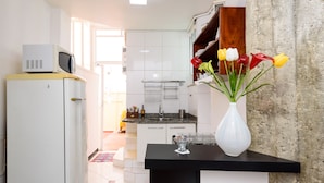 Eine moderne Küche mit weißen Schränken, einer schwarzen Arbeitsplatte und einer weißen Vase mit Blumen.
