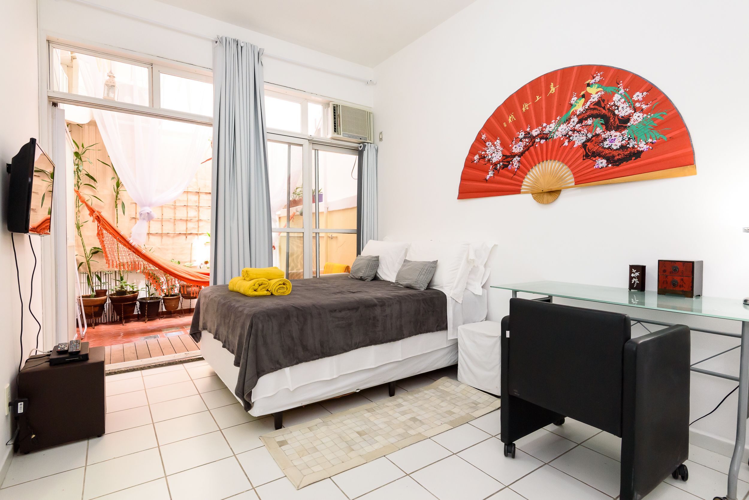 Un dormitorio moderno con una cama, un escritorio y un ventanal grande.