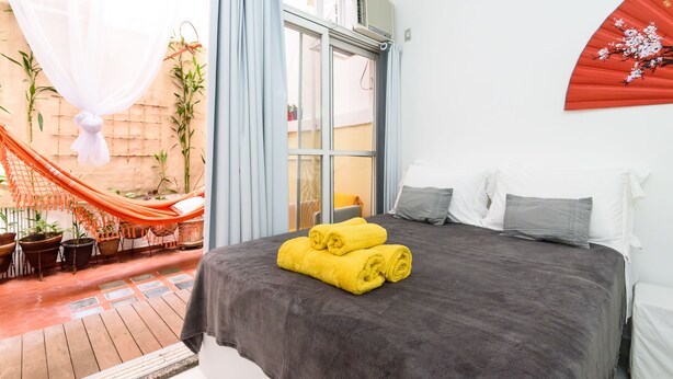 Ein Schlafzimmer mit einem Bett, Kissen, einem Fenster und einem roten Ventilator.