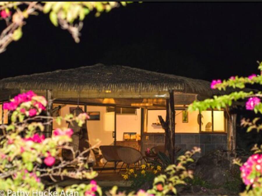 Una casa con techo de paja, zona de comedor y cocina a la vista.