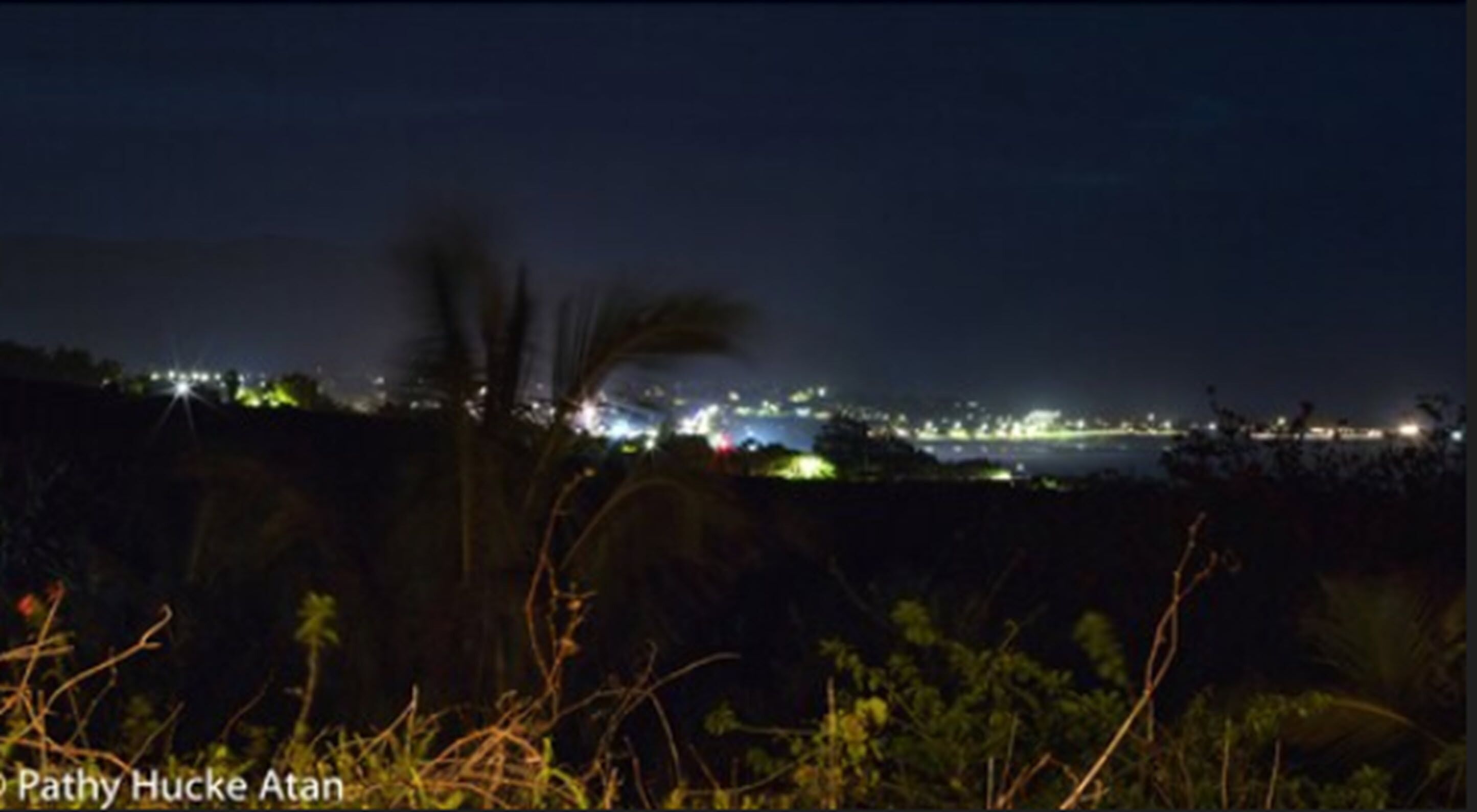 A nighttime view of a coastal area with distant city lights.