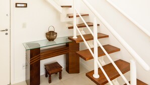 A modern staircase with wooden steps and white railings, leading to a glass desk with a woven basket. - Omar do Rio - Apartamento CobR (Rio de Janeiro)