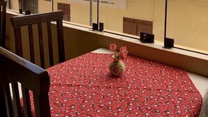 A balcony with a red tablecloth, a wooden chair, and a vase with flowers. A sign with the name 'Barrington' is visible in the background. - Valle del Inca (Cajamarca)