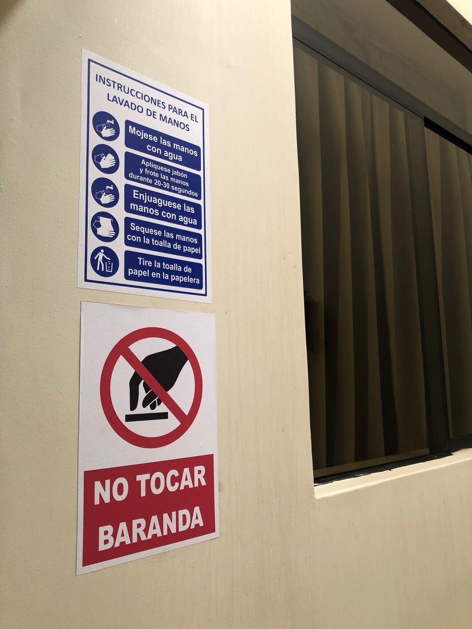 A wall with two signs: one with handwashing instructions and another prohibiting touching the bar.