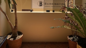 A room with a window overlooking a tiled roof, potted plants, and a sign with the name 'BARRINGTON'. - Valle del Inca (Cajamarca)