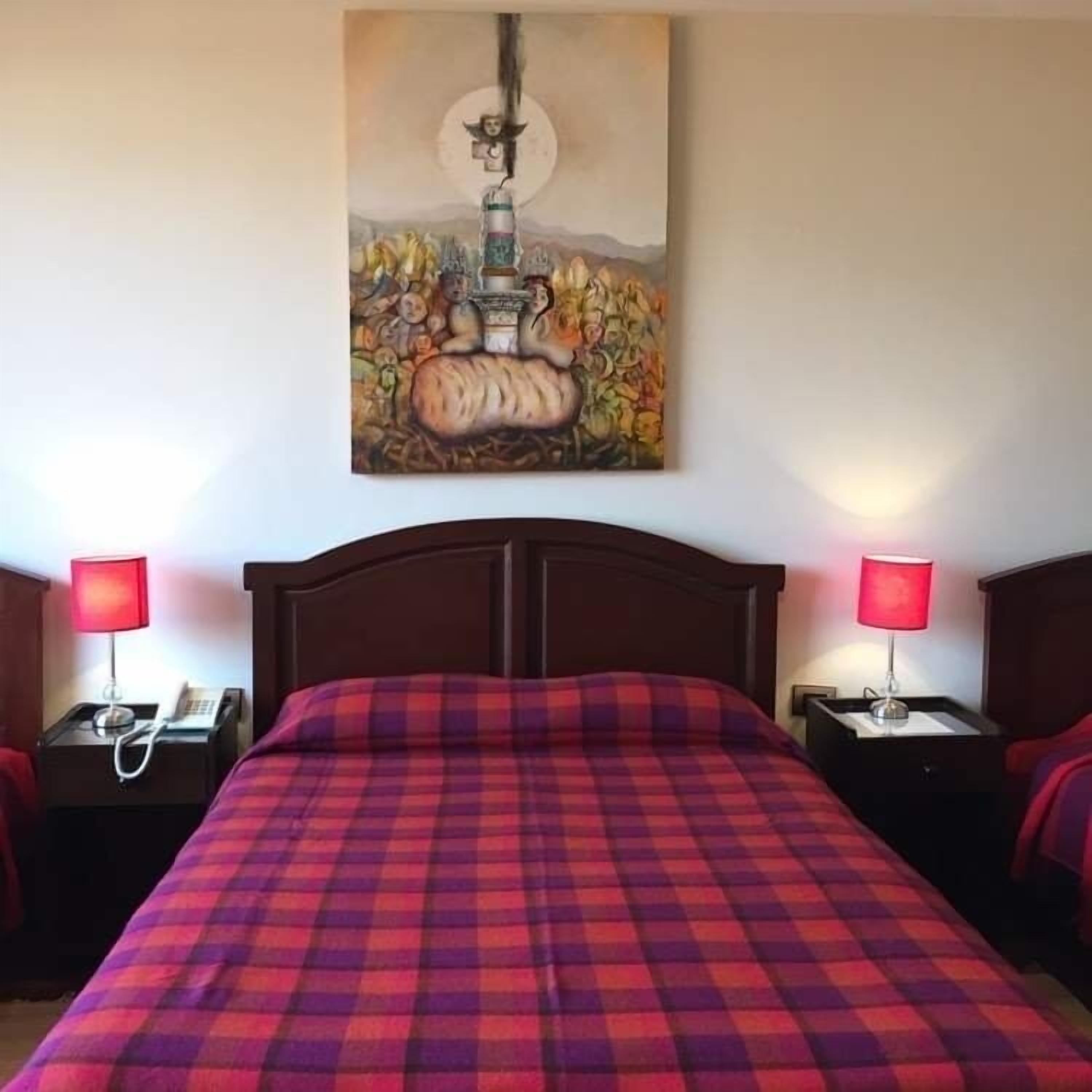 Une chambre d’hôtel avec un grand lit, deux tables de chevet avec des lampes et un tableau au mur.