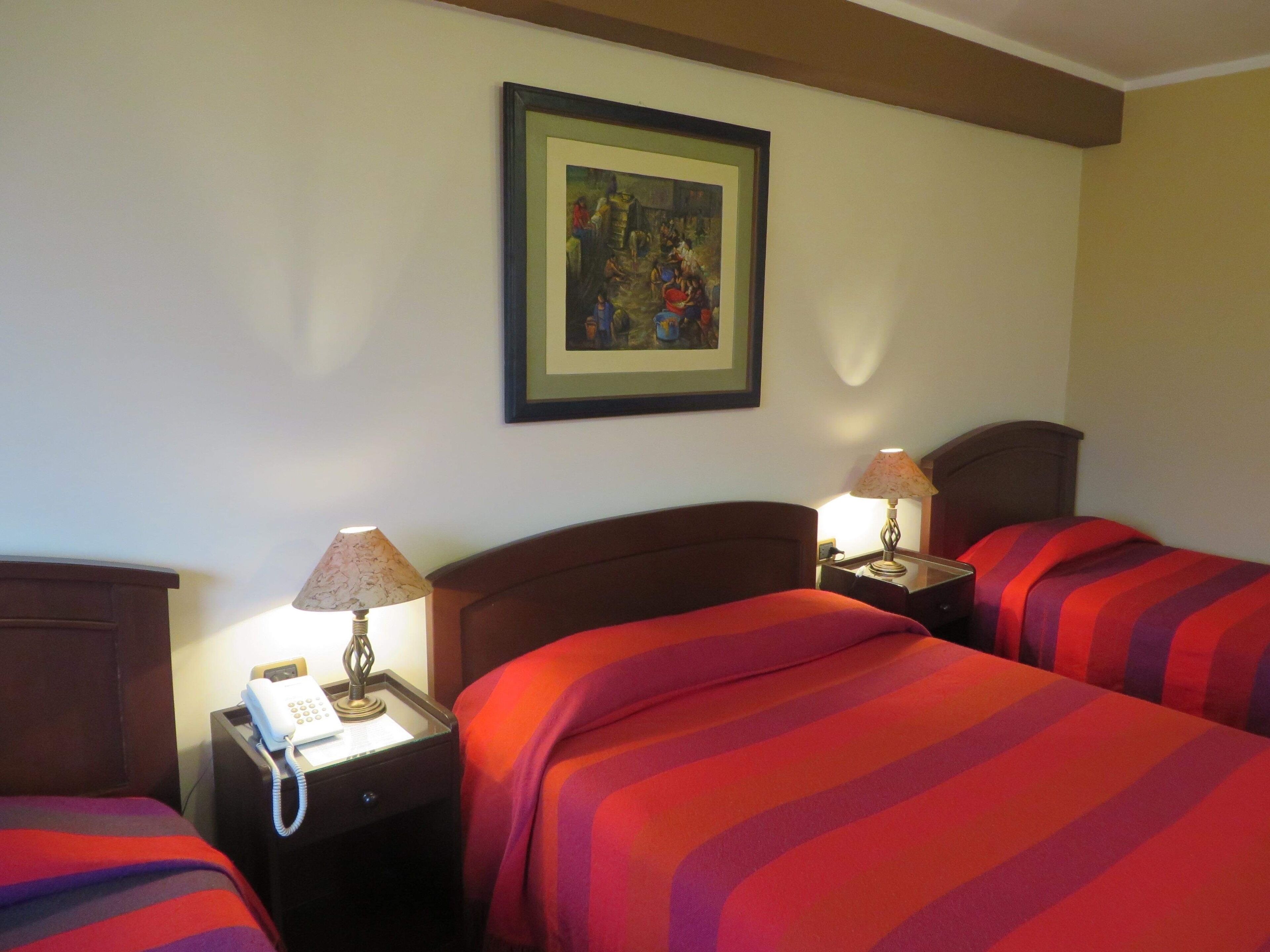 A hotel room with two beds, a telephone, and two bedside lamps.