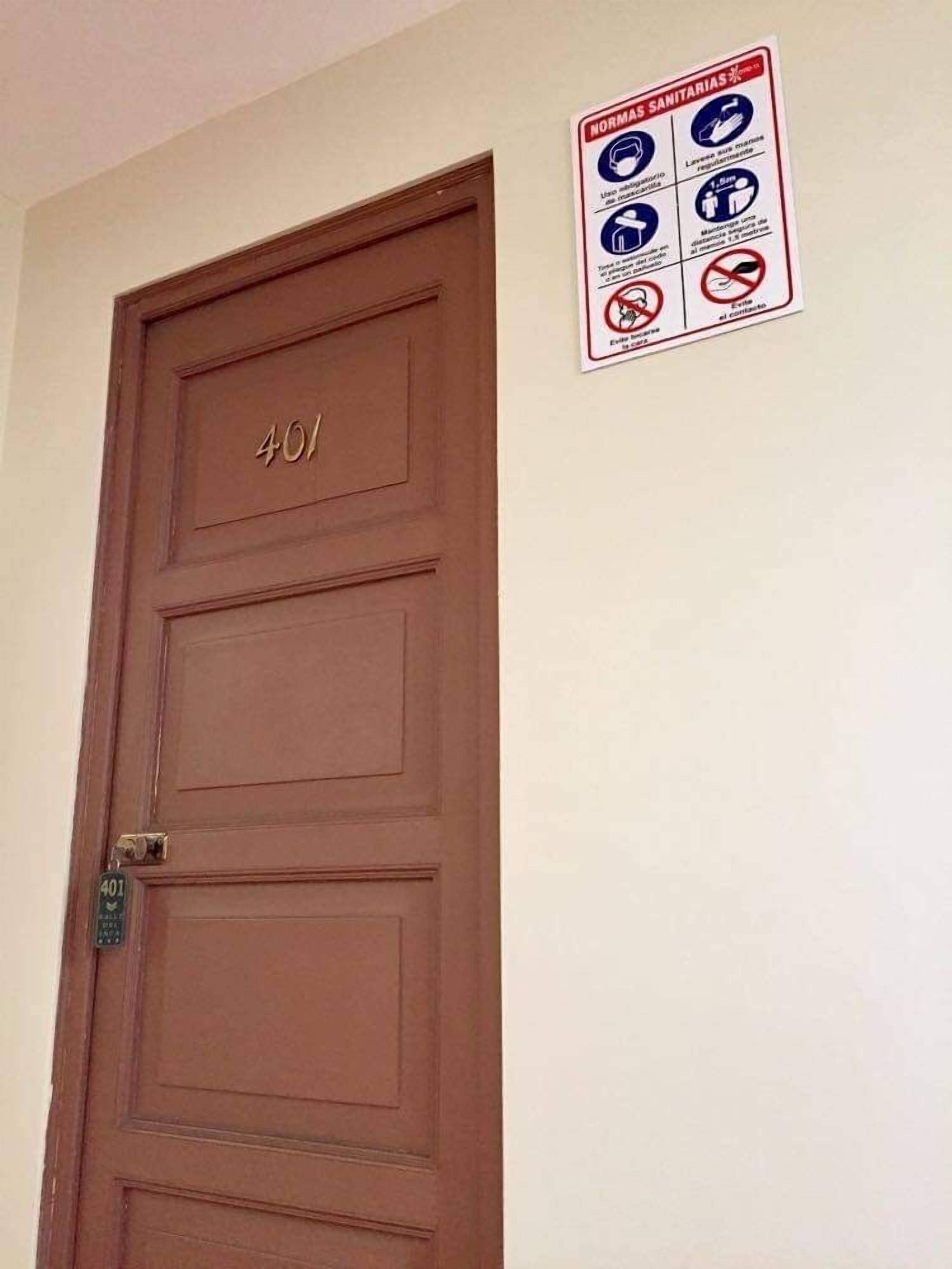A brown door with the number 401 and a sign with health and safety guidelines on the wall.