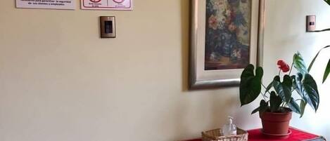 Una pared con dos carteles de seguridad, un cuadro enmarcado y una pequeña mesa con una planta.
