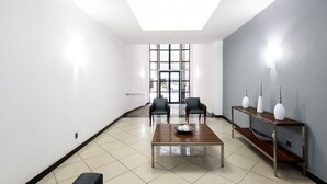 A modern conference room with a large table, two chairs, a bench, and a console table with lamps. - Omar do Rio - Apartamento FO407 (Rio de Janeiro)