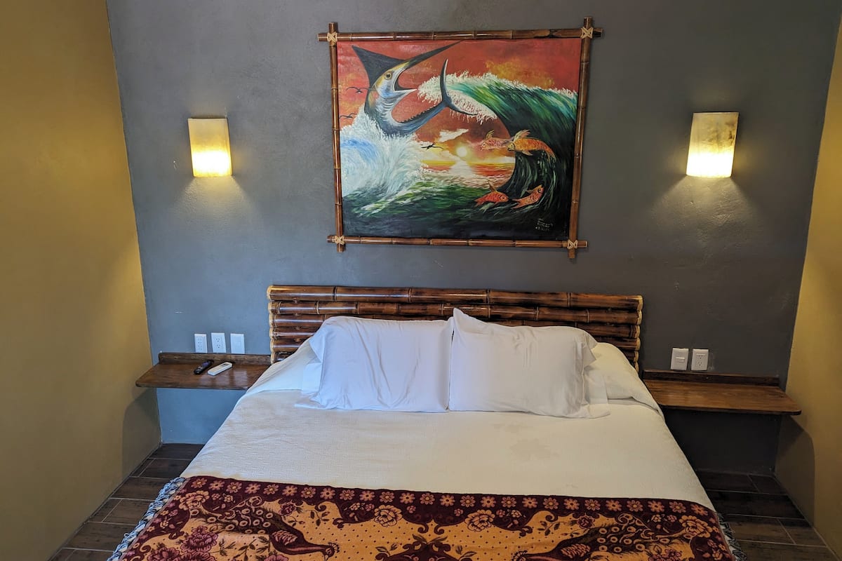 A bed with white bedding, a decorative pillow, and a patterned throw.