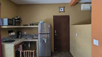 Una cocina compacta con ventilador de techo de madera, un refrigerador, un microondas y un lavamanos.