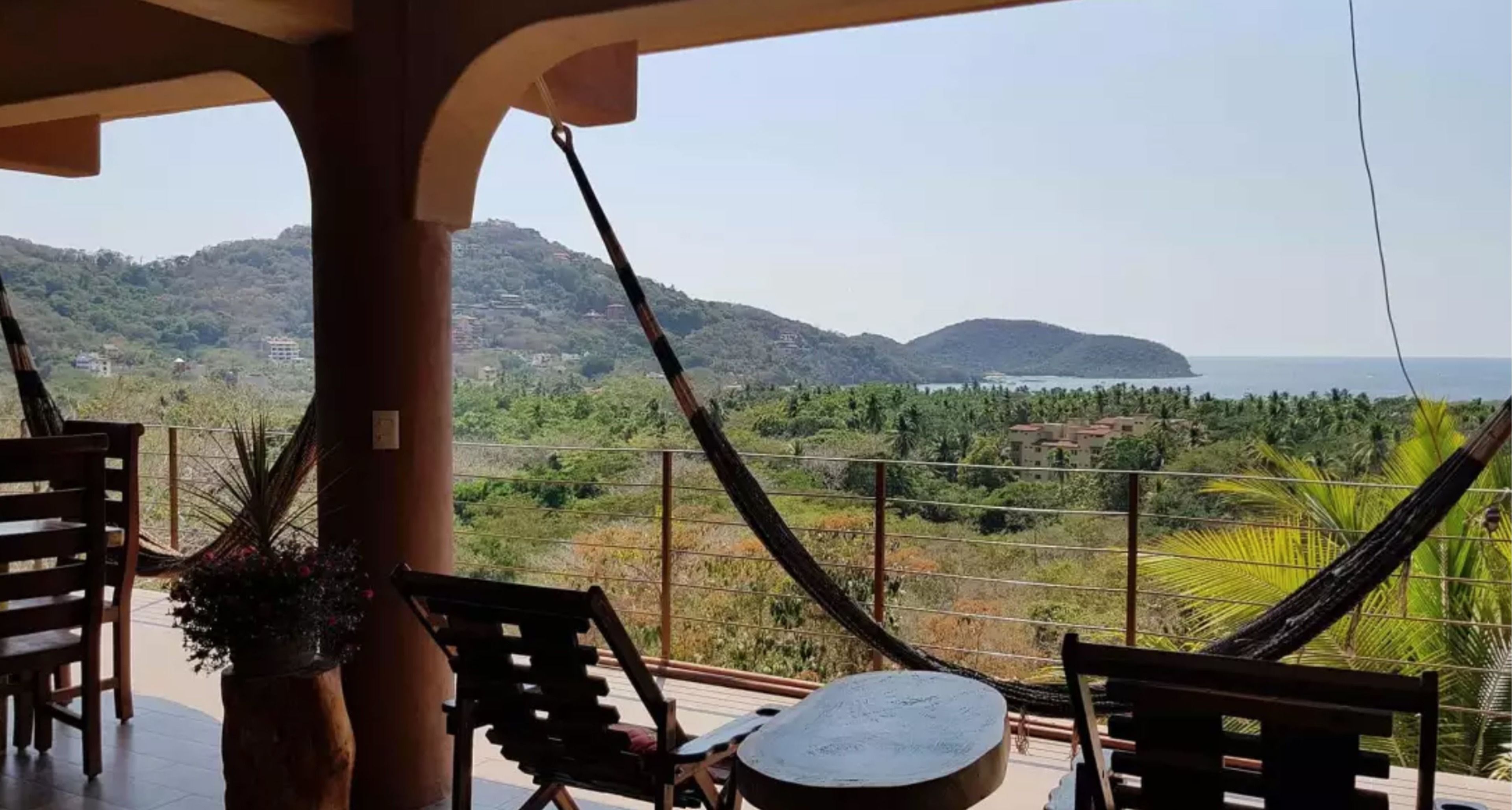 A balcony with a view of a mountainous landscape and the sea.