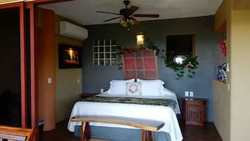 Un dormitorio con cama, ventilador de techo, ventana y mesita de noche.