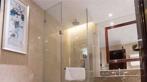 A bathroom with a glass shower enclosure, a toilet, a sink with a mirror, and a framed artwork on the wall. - Bo Jue Hotel (Shanghai)