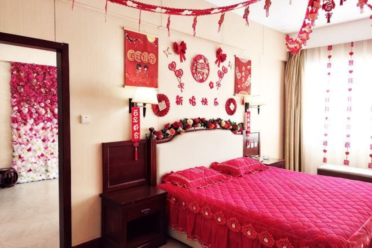 Una camera da letto con un letto, comodini e una parete decorata con elementi rossi e dorati.