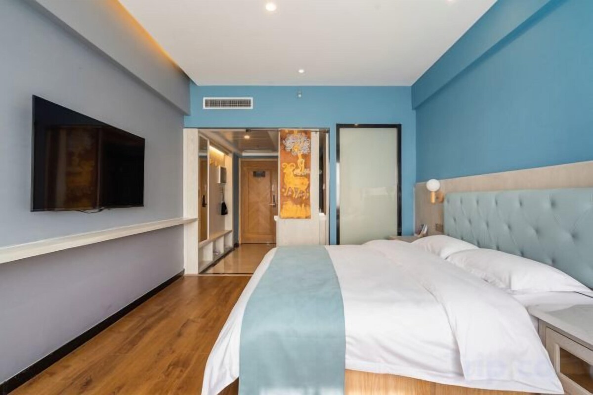 Una camera d'albergo con un letto, una televisione e una porta che dà su un'altra stanza.