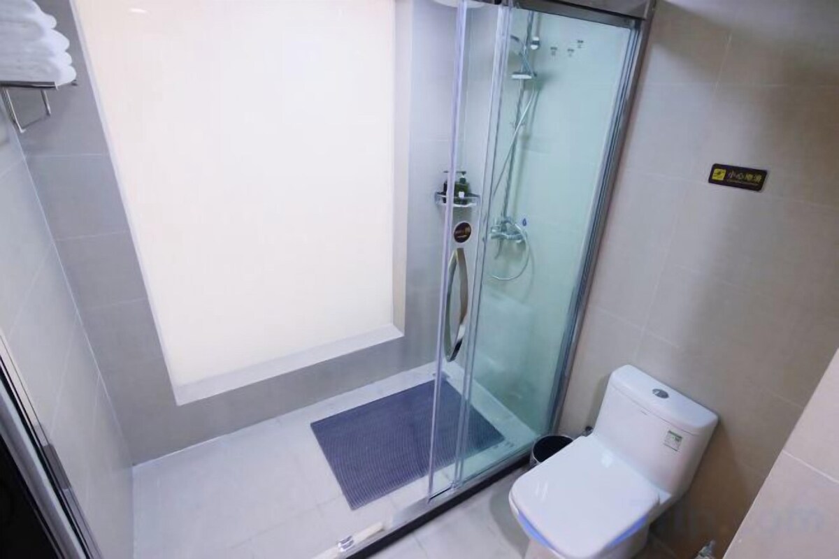 Cabina doccia in vetro con servizi igienici adiacenti.