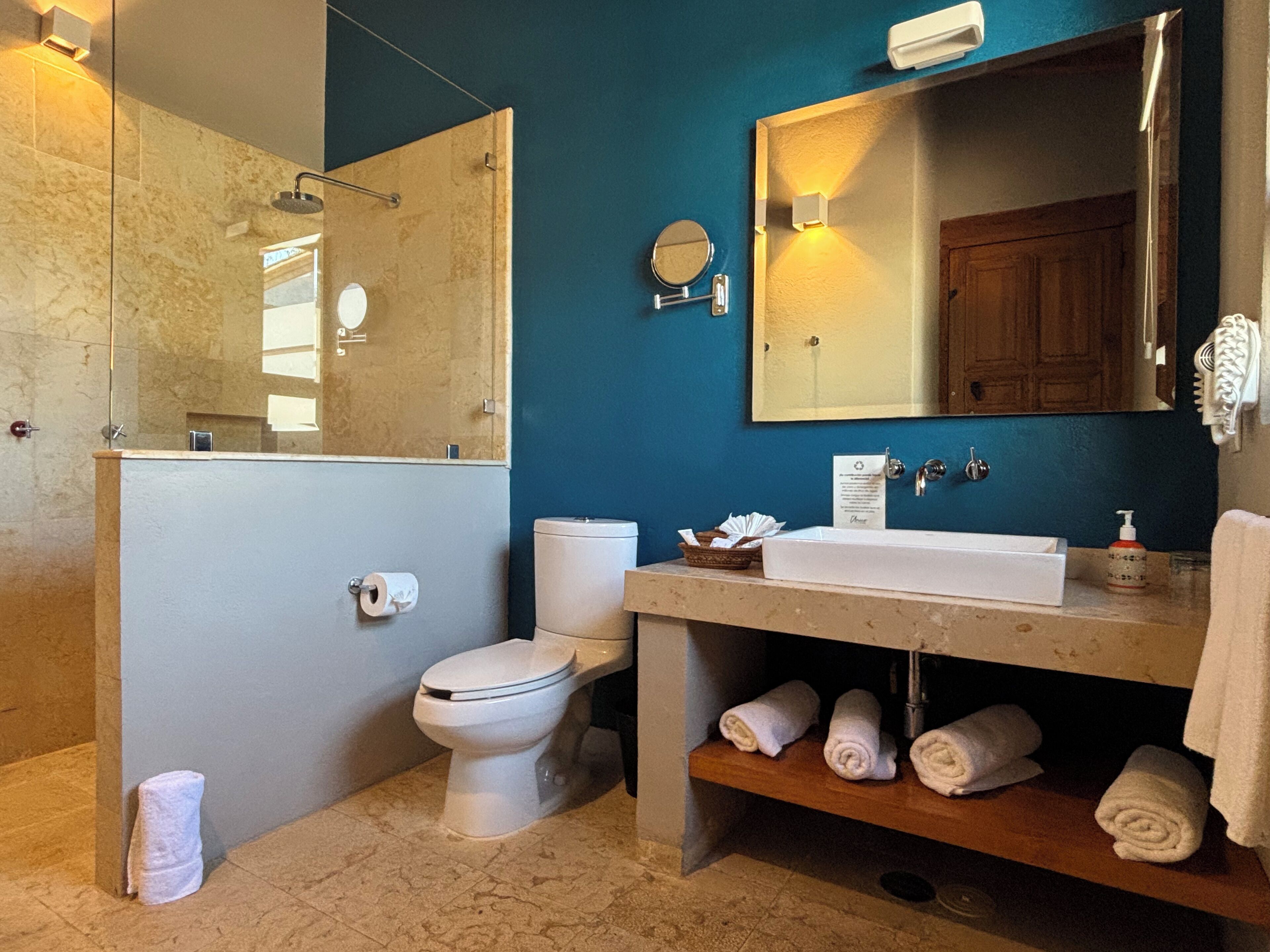 A bathroom with a toilet, sink, and mirror.