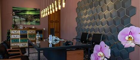 A modern office with a glass desk, a hexagonal wall design, and a painting on the wall.