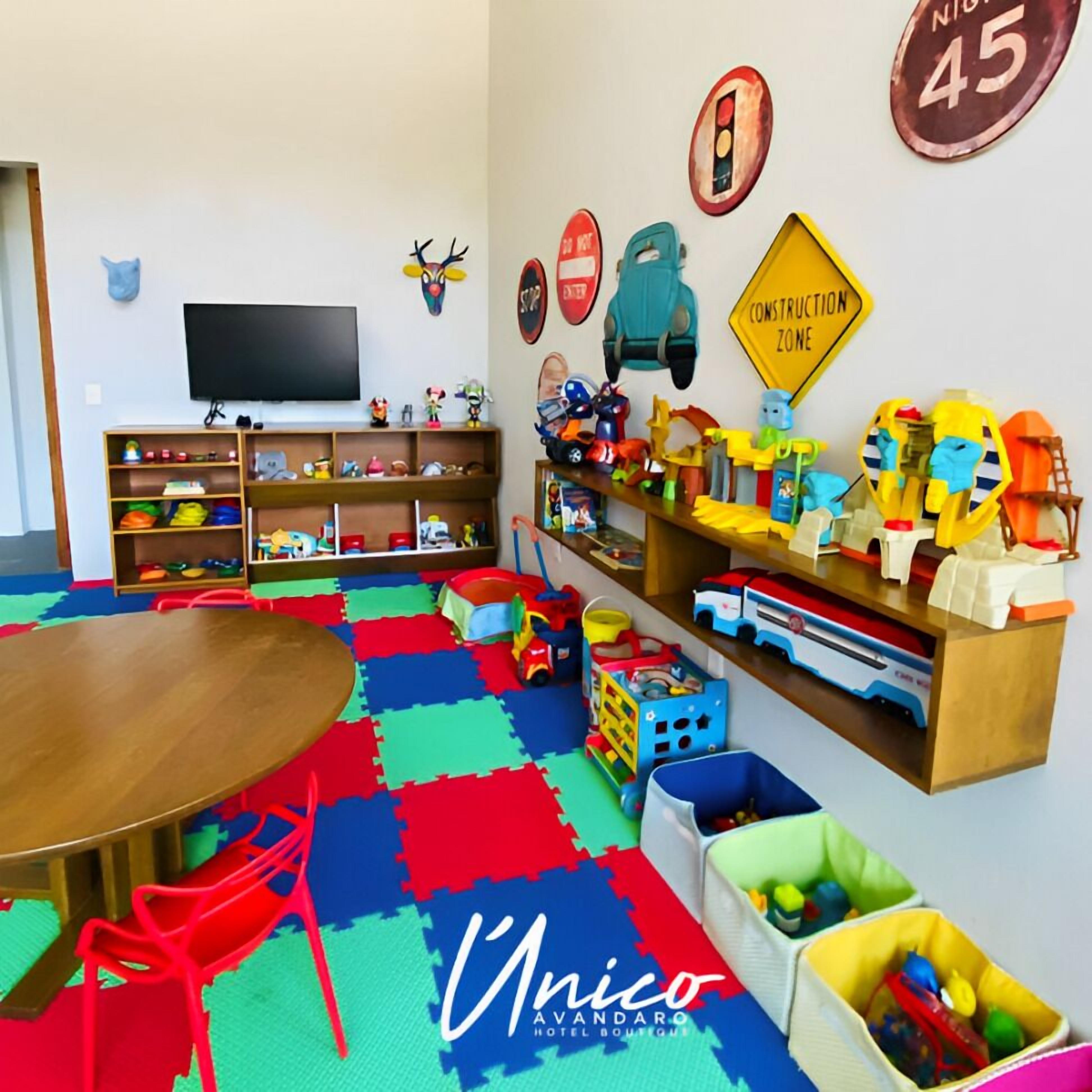 A children's playroom with a round table, colorful play mats, and various toys.