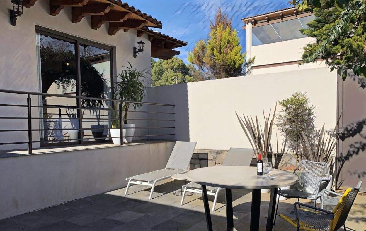 Un patio con mesa y sillas, barandilla y plantas en macetas.