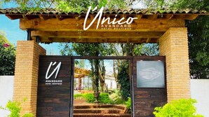 De ingang van Unico Avandaro Hotel Boutique, met een houten pergola, stenen trappen en beplanting.