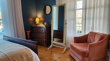 A bedroom with a bed, a dresser, a mirror, a chair, and a window with curtains.