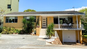 Une maison de plain-pied avec un toit en tuiles, un garage et un petit porche doté d’une balustrade.