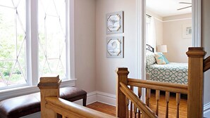 A room with a wooden staircase, a bench, and two framed pictures on the wall.