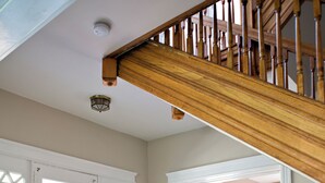 A wooden staircase, a patterned rug, and a door with a window.