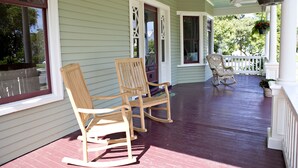 A porch with two rocking chairs and a white railing.