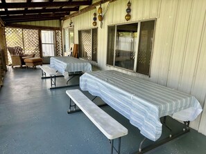 A covered outdoor seating area with tables and benches, a wooden ceiling, and a lattice fence in the background. - 5 Bedroom Lake Access House and Entertainment Bldg  (Fremont)