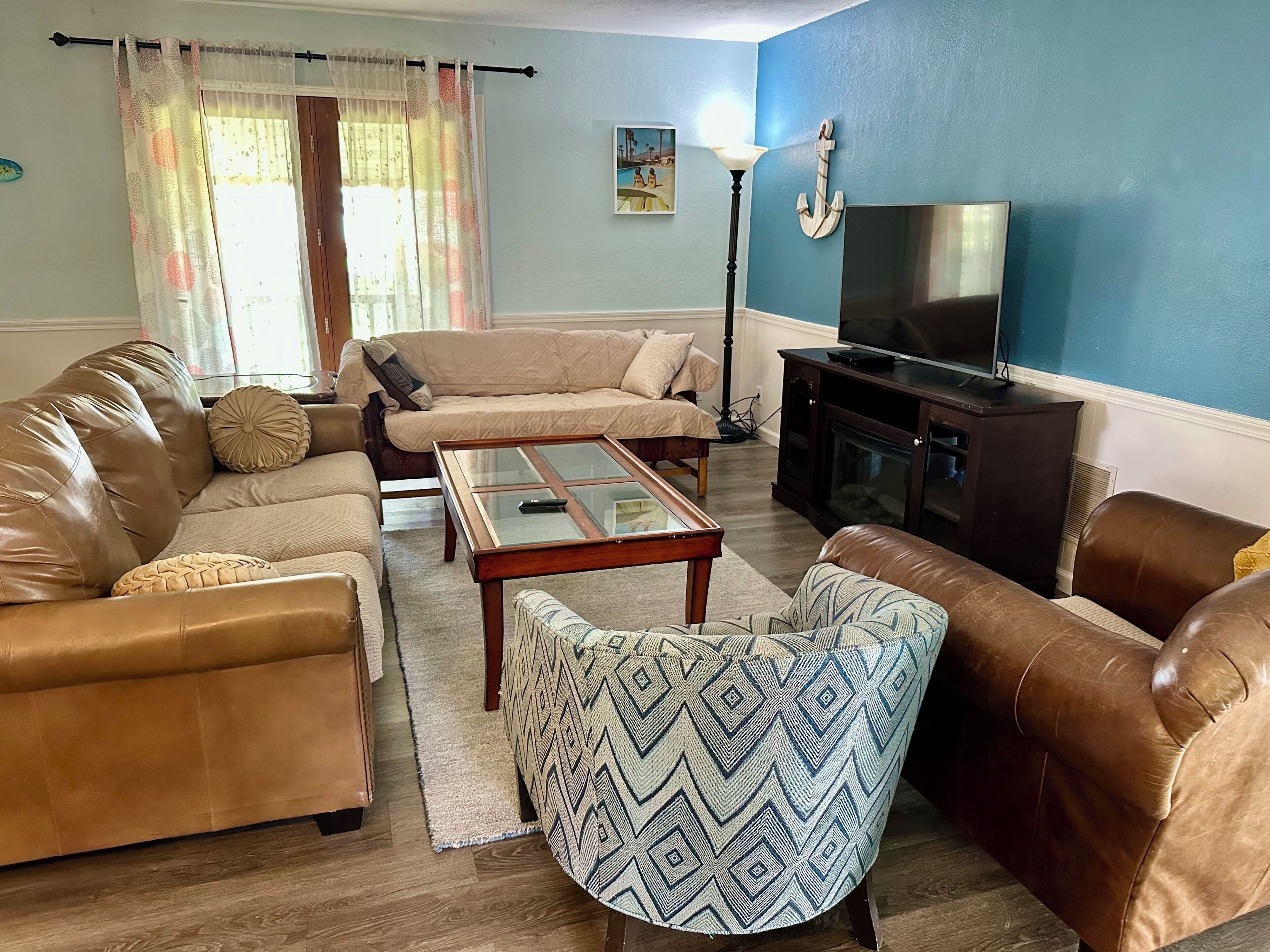 A living room with a sofa, armchair, coffee table, and a television.