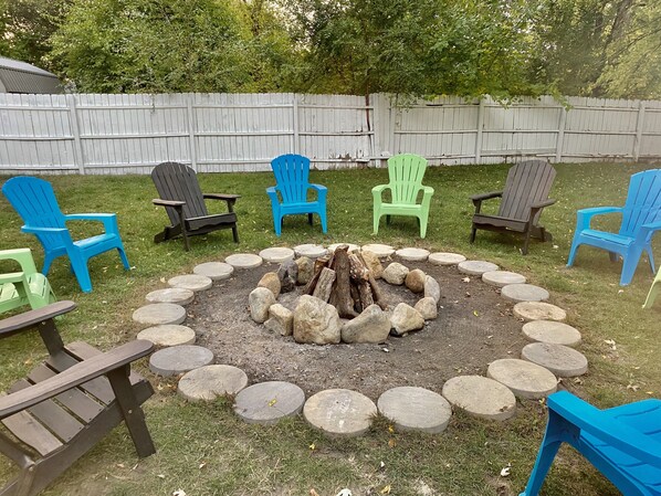 A backyard with a fire pit surrounded by stone steps and colorful Adirondack chairs. - 5 Bedroom Lake Access House and Entertainment Bldg  (Fremont)