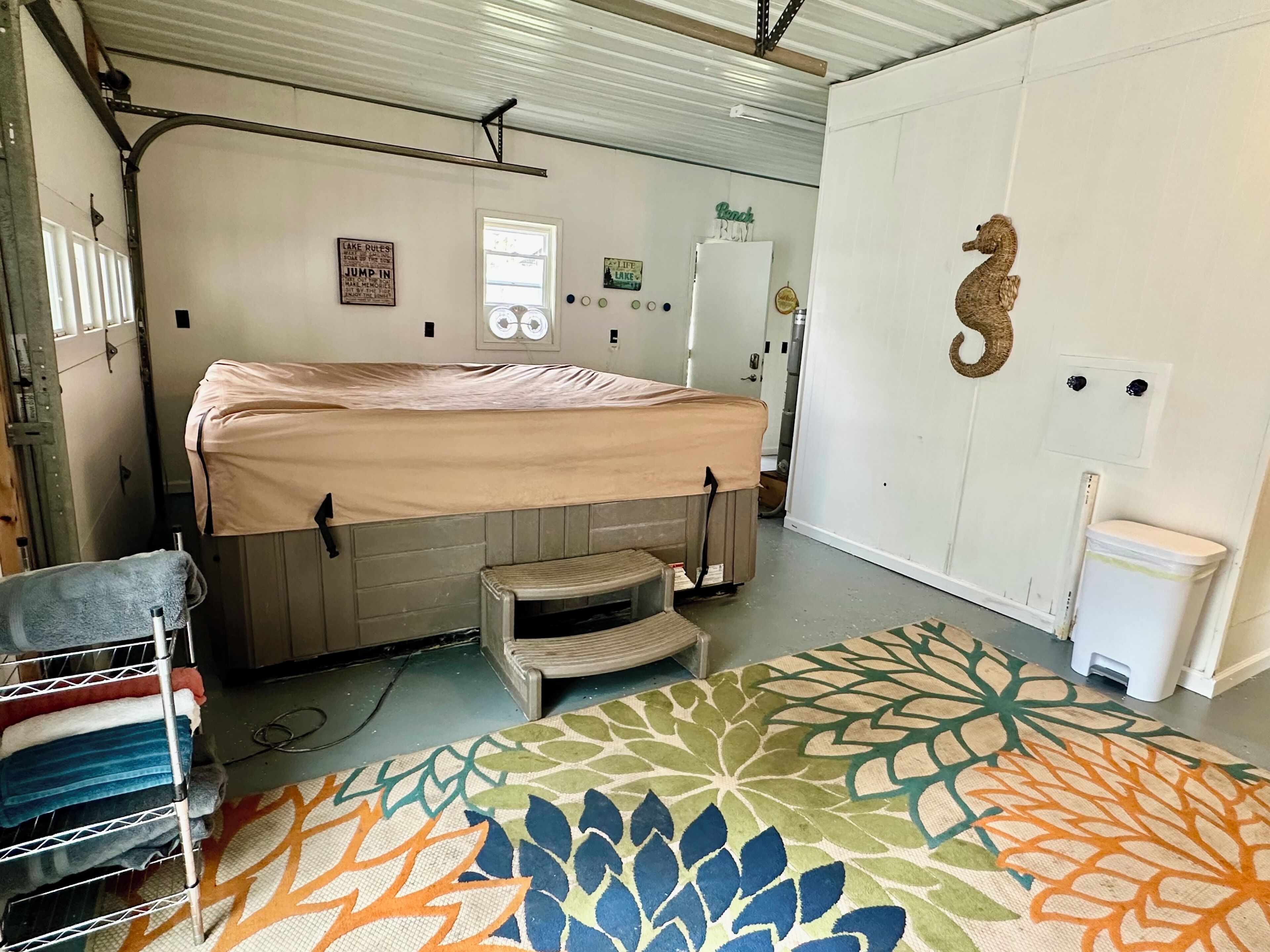 Ein kleines Zimmer mit einem Etagenbett, einem kleinen Hocker, einer Treppe, einem bunten Teppich, einer Seepferdchen-Dekoration und einer weißen Tür.