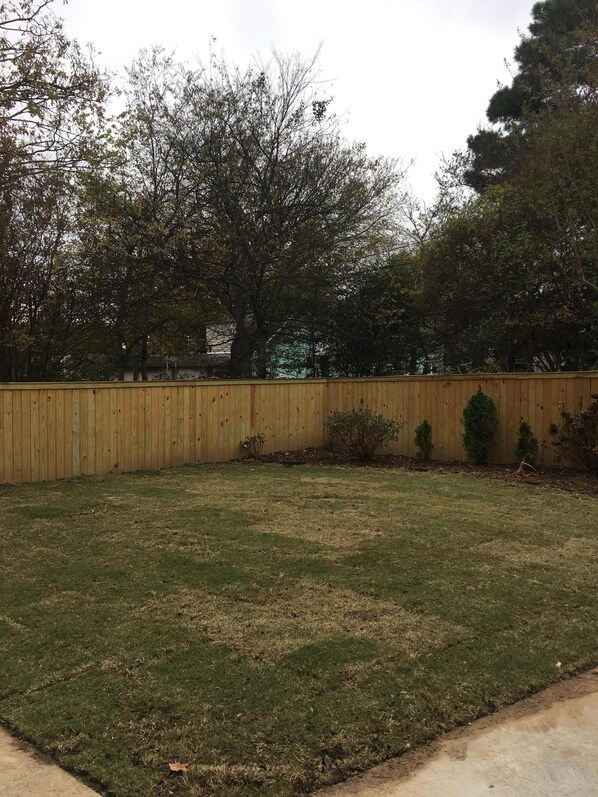 A fenced backyard with a grassy lawn and a wooden fence. - Fantastic house between Hillcrest neighborhood and Downtown LR (Little Rock)