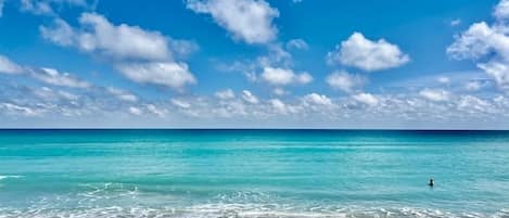 Une plage à l’eau turquoise et limpide, bordée d’un rivage sablonneux.