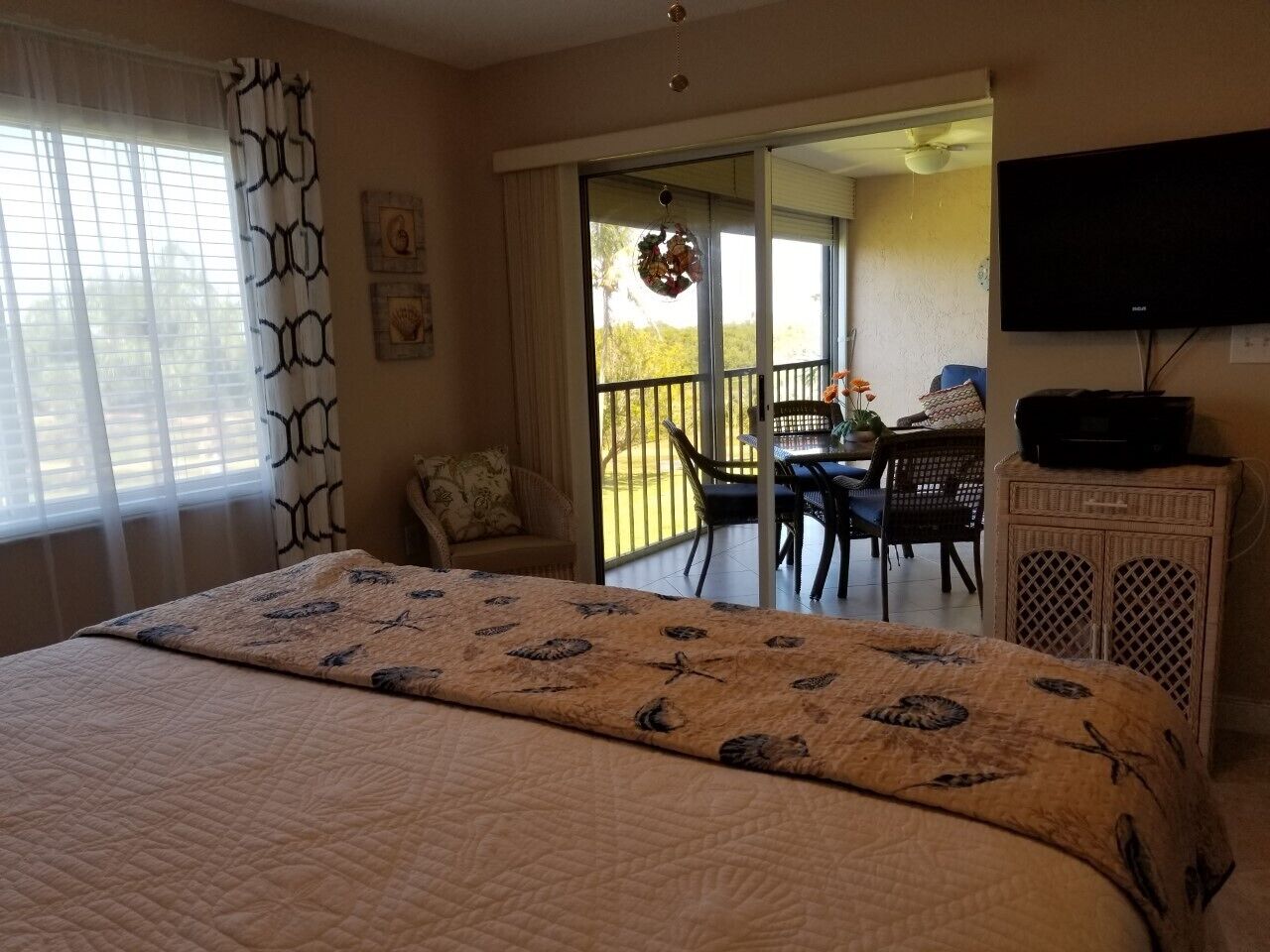 Une chambre avec un grand lit, une télévision et un balcon équipé d’une table et de chaises.