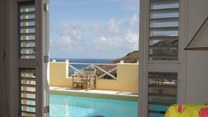 Une chambre avec vue sur une piscine et la mer.